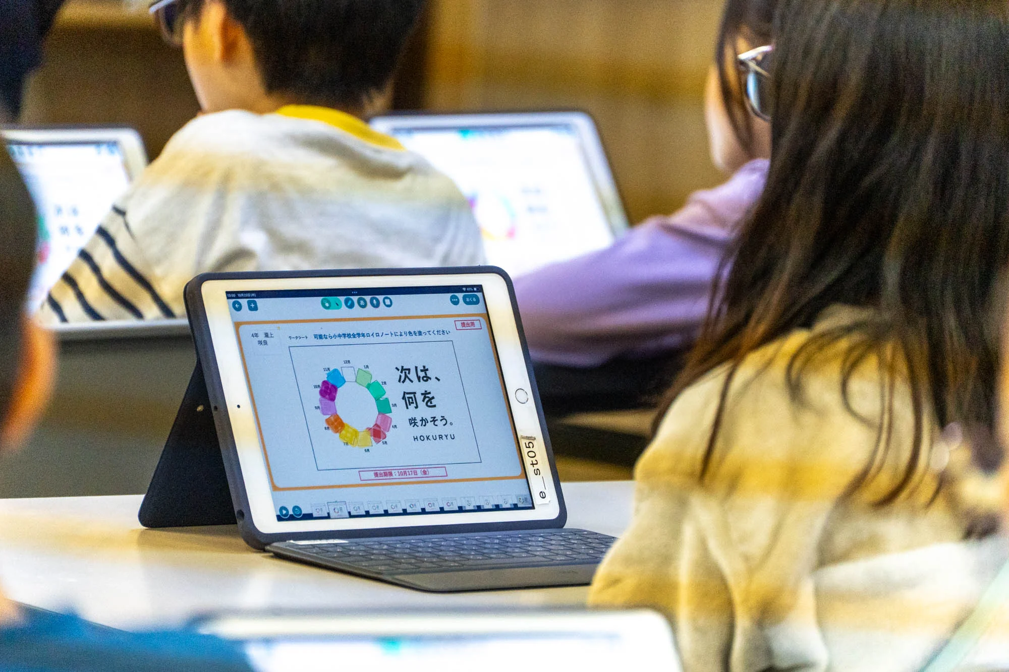 オンライン授業を受ける子どもたちの手元にはタブレットがあり、自分なりの色を塗ったワークシートが開かれている。